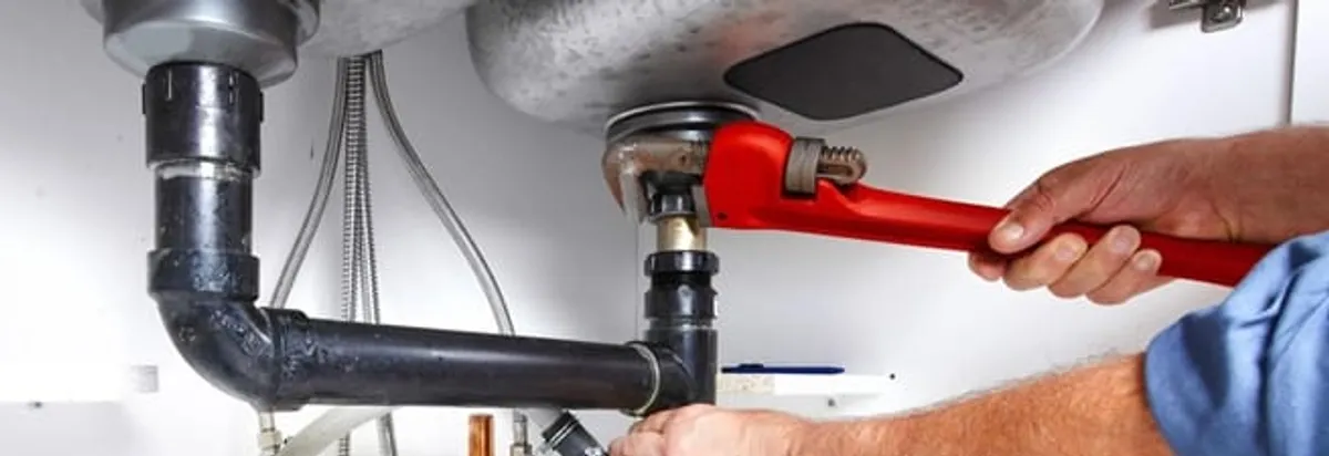 Garbage disposal repair technician tightening the sink drain and disposal connection in Phoenix, AZ